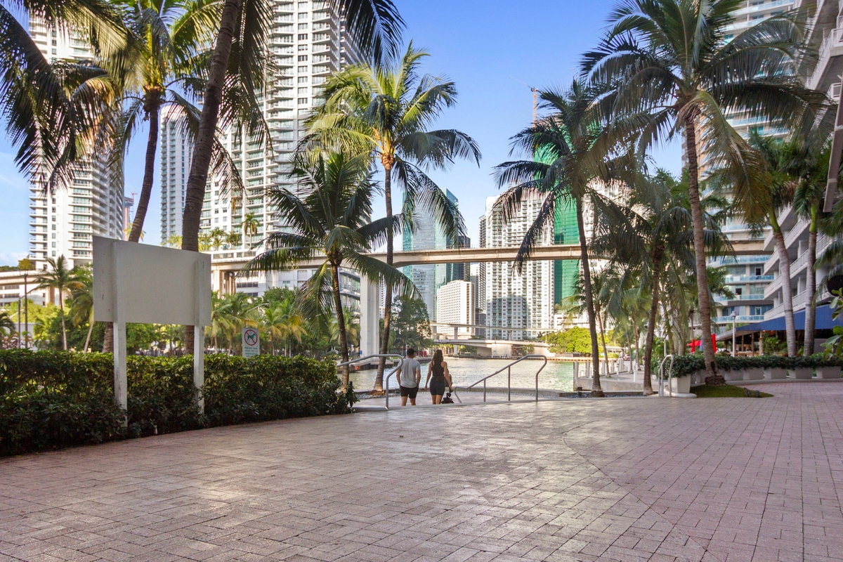Miami River walkway with palms and Brickell towers beside Latitude One