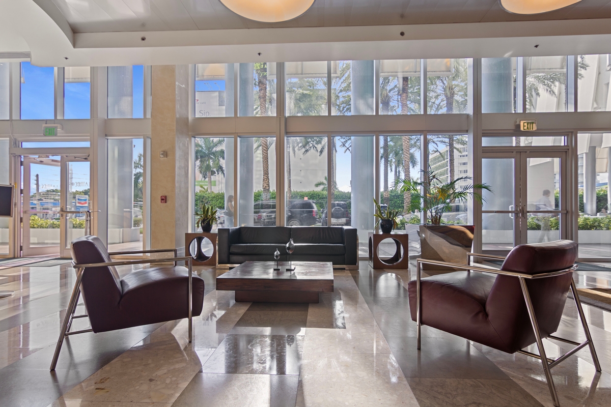 Latitude One lobby lounge framed by curtain-wall glazing overlooking the Miami River area