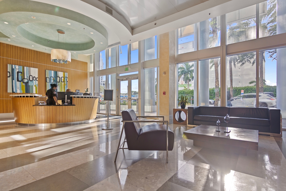 Lobby concierge desk and seating beneath the building's curved glass facade