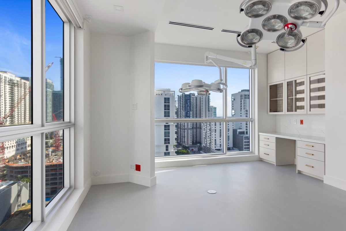 Surgical and procedure room with ceiling-mounted lighting, custom cabinetry and Brickell skyline views